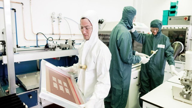 Lab technicians, white and green suits in a lab