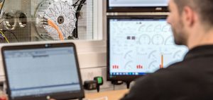 Scientist using a laptop with a motor in the background